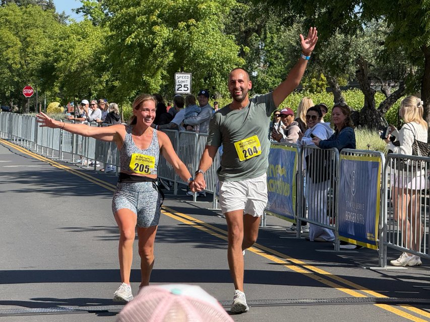 A couple crossing the finish line hand in hand