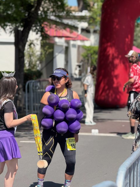 A runner dressed as a bunch of grapes receiving her medal