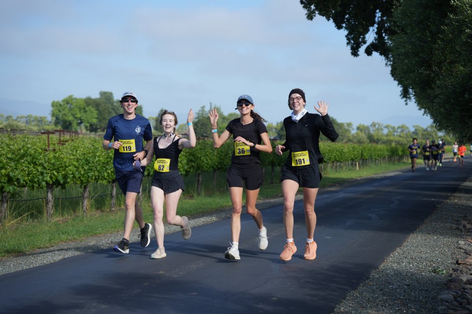 Runners waving on a vineyard road